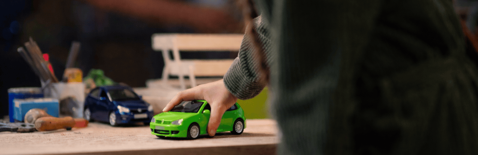 Enfant jouant avec des voitures miniatures, illustrant comment Cardoen transforme une voiture d’occasion en voiture reconditionnée.